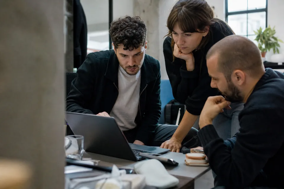 Product team gathered around one laptop discussing what users did