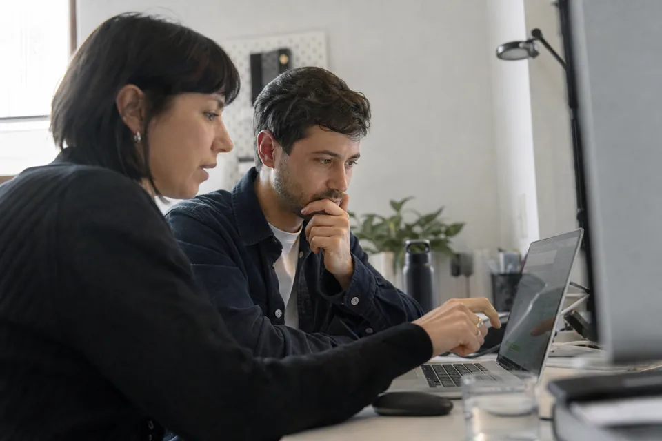 Two colleagues comparing analytics tools on a laptop