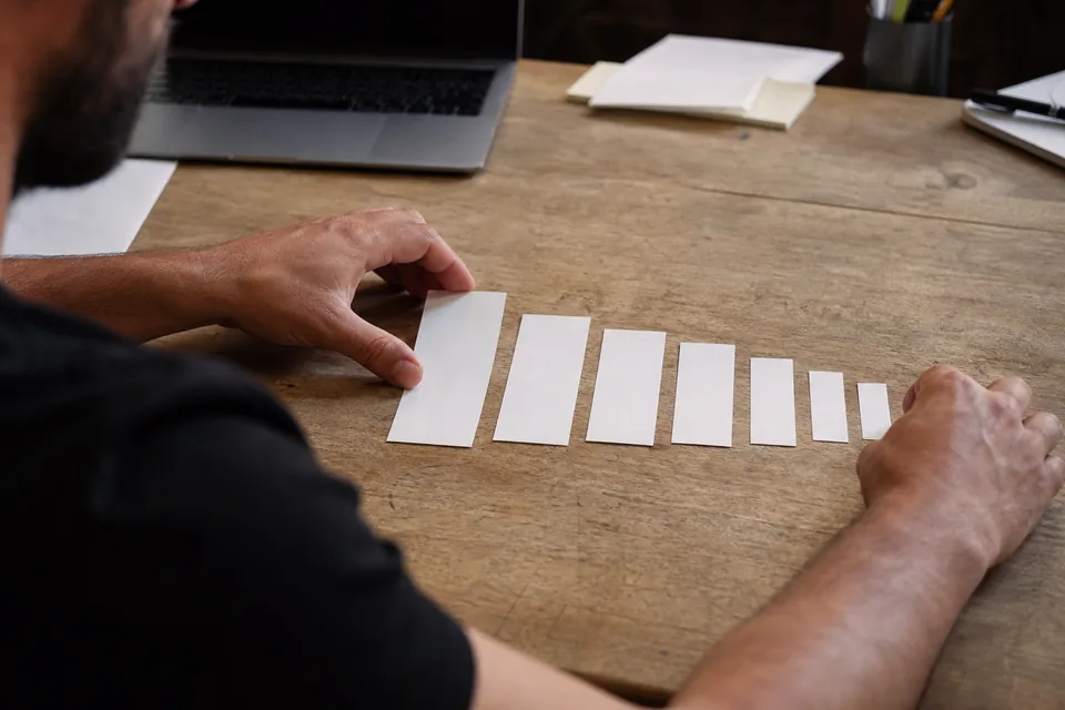 Growth analyst laying out paper cards in a narrowing funnel, one card per signup step