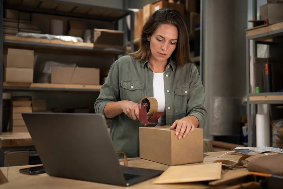 Store owner packing orders next to a laptop used to run two online shops