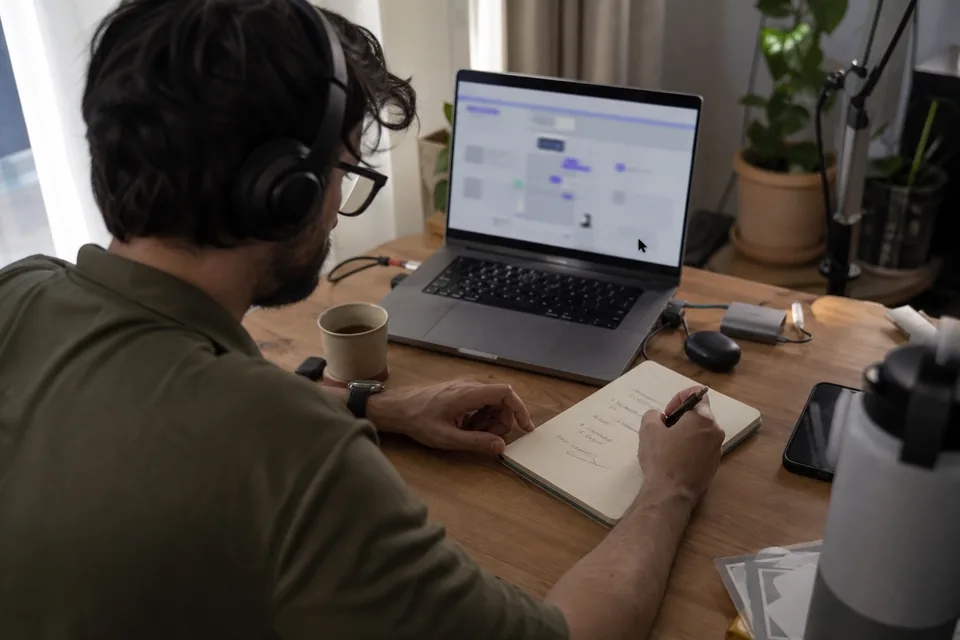 Analyst taking notes from a recorded user session on a laptop